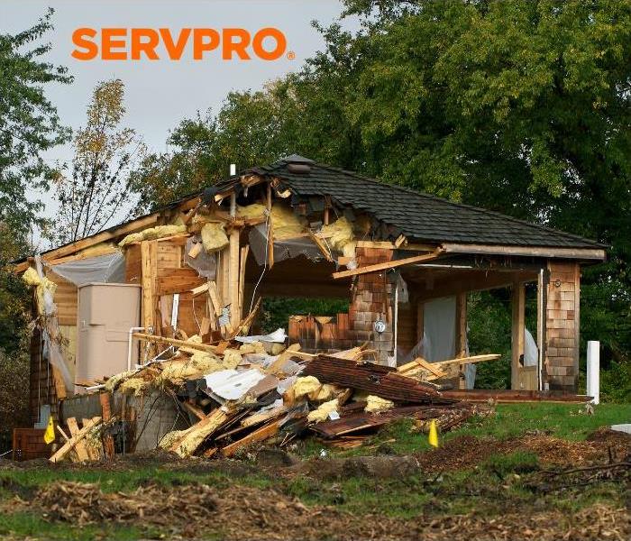 house damaged by storm and servpro logo